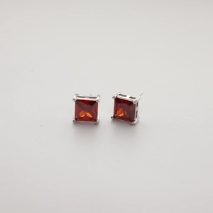 Detail of red square-cut zircon stud earrings with silver four-prong settings