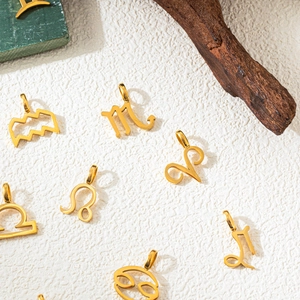 Detailed close-up of golden zodiac pendants on a textured white surface with natural decor