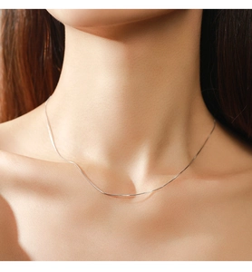 Detailed close-up of a minimalist S925 sterling silver heart snake chain on a model neck