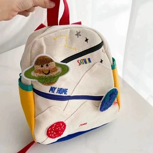 Detail view of colorful planet embroidery and Saturn patch on cream canvas kids backpack