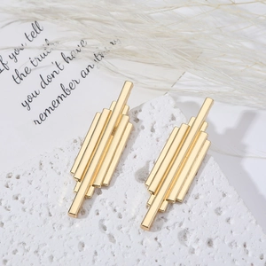 Minimalist gold geometric tassel earrings with long tiered bars on a white textured base