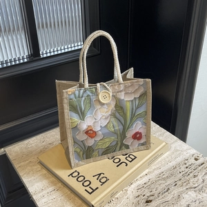 Detail of linen tote bag with floral print and rustic wood button closure on marble
