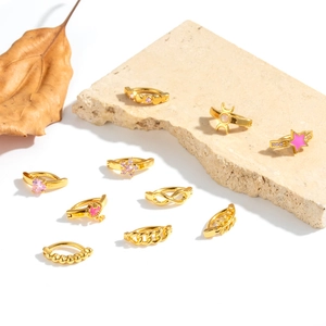 Goldene Bauchnabelpiercings mit Mond- und Sternanhängern auf einem Naturstein