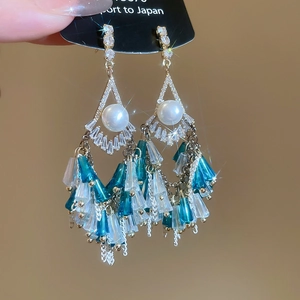 Detail of vintage beaded tassel earrings with blue and white beads and leaf accents
