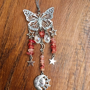 Detail of metal suncatcher with butterfly, moon, and sun charms with red crystal stones