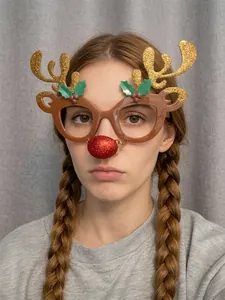 Close-up of reindeer Christmas glasses with gold antlers and red nose for party fun