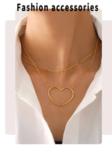 Detail einer doppellagigen Goldkette mit hohlem Herzanhänger, am Model getragen