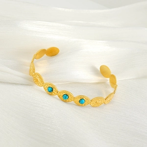Détail du bracelet rigide en acier titane plaqué or 18K avec perles turquoise sur soie