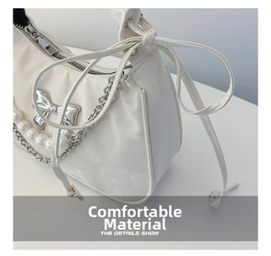 Close-up of white dumpling bag showing silver bow charm and pearl chain detail