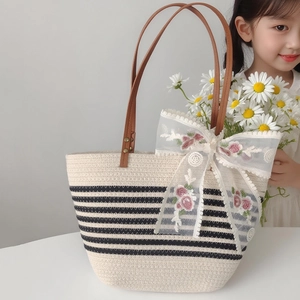 Detail of woven straw tote with floral lace bow and brown leather handle rivets
