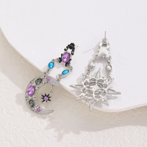 Detailed view of silver asymmetric moon and sun drop earrings with purple and blue gems