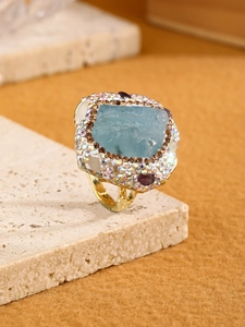 Detail of blue raw stone ring with multi-color diamonds and vintage gold hammered band