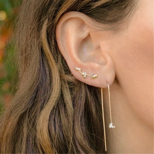 Detail of asymmetric gold S925 earrings with sparkling stones and elegant long chain