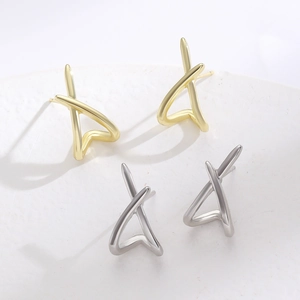Vue macro de boucles d'oreilles géométriques en X minimalistes dorées et argentées