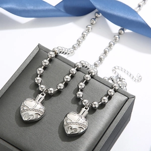 Detailed view of silver heart urn necklaces with bead chains on a jewelry box