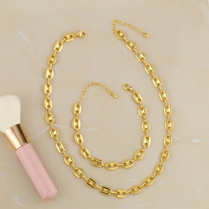 Detail of gold pig nose chain necklace and bracelet set with lobster clasp on marble