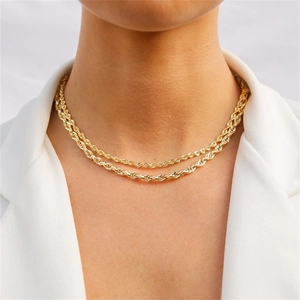 Detalle de collares de cadena de cuerda dorada en capas sobre un blazer blanco