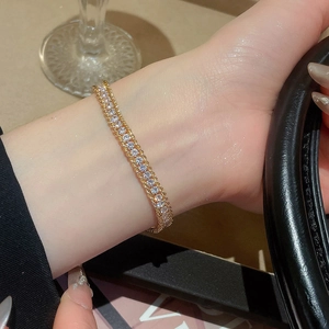 Detail of a sparkling gold-plated chain bracelet with rhinestones worn on a female wrist