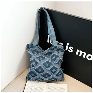 Detail of denim tote bag featuring quilted star patterns and raw fringe edge textures