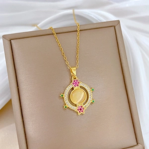 Detail of gold necklace featuring a yellow cat eye stone pendant with colorful zircons