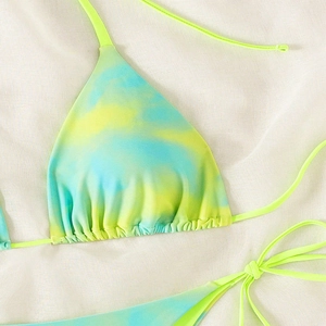 Flat lay detail of a tie-dye bikini set with fluorescent green and blue lace-up straps
