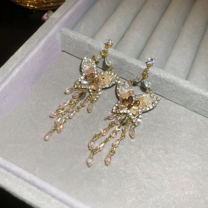 Detail of luxury gold butterfly tassel earrings with sparkling crystals and pink beads