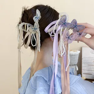 Dettaglio del fermaglio per capelli a farfalla ricamata con perle e nappe di nastro