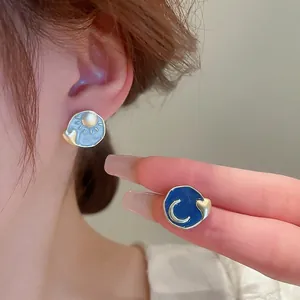 Asymmetric sun and moon heart stud earrings with blue enamel in gold finish