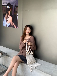 Close-up of beige woven bag featuring wooden circular handles and long fringe tassels
