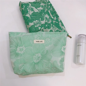 Detail of green floral canvas and jacquard makeup bags with simple wish woven labels