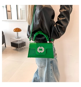 Detail of green leather handbag featuring a crystal square buckle and cloud-like handle