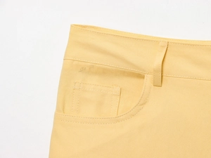 Détail de pantalon large en sergé jaune avec passants de ceinture et poches