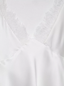 Détail macro de la robe en satin blanc avec dentelle raffinée sur l'élégant décolleté en V