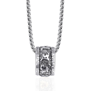 Détail du pendentif cylindrique argenté avec motifs de nuages et sanskrit sur chaîne