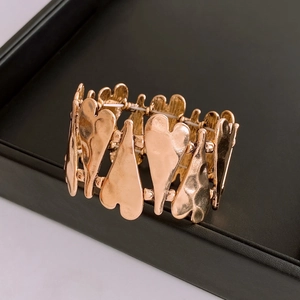 Macro detail of rose gold heart bracelet featuring vintage hammered metal texture and elastic