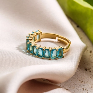 Detail of adjustable gold ring with rectangular blue stones on a beige satin background