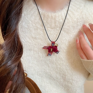 Dettaglio della collana con orsetto floccato rosso su maglione bianco morbido