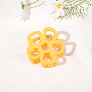 Detailed top view of a matte yellow flower-shaped hair claw clip with cutout petals