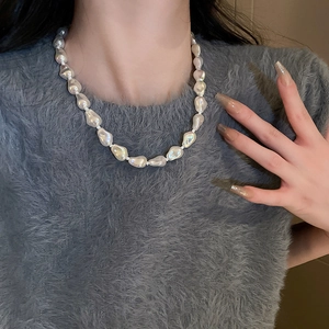 Close-up of irregular large white pearls necklace on model with elegant styling