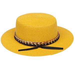 Detailed texture of yellow boater straw hat with gold chain and black ribbon bow