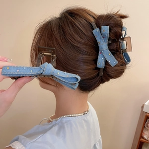 Detail of denim bow hair claw clips with colorful rhinestones on a female model