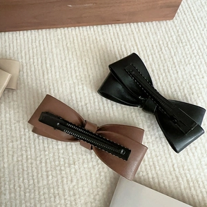 Detail of soft PU leather bow hair clips in brown and black with stitching and metal base