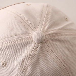 Close-up of beige twill cotton baseball cap top with stitched seams and eyelets