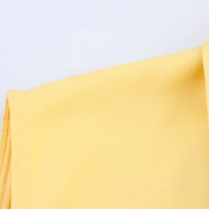 Close-up of yellow twill fabric showing detailed stitching and high-quality textile texture