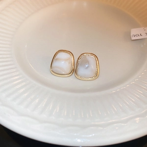 Detail of vintage French resin earrings with golden metal edges in a ceramic plate