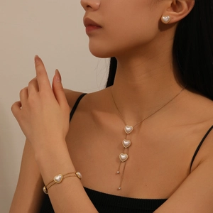 Gold heart pearl jewelry set with tassel necklace and earrings on a model
