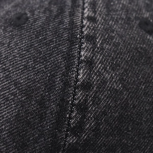 Gros plan sur le denim gris délavé avec œillet brodé et détails de couture du chapeau