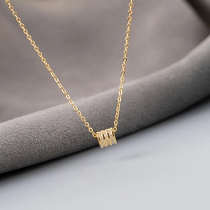 Macro shot of gold cylinder pendant with multiple rows of sparkling white zircons
