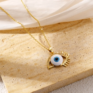 Golden Evil Eye pendant necklace with blue eye element on natural stone background