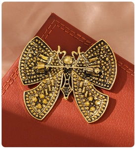 Detailed view of vintage gold butterfly brooch with intricate metal textures and pin back